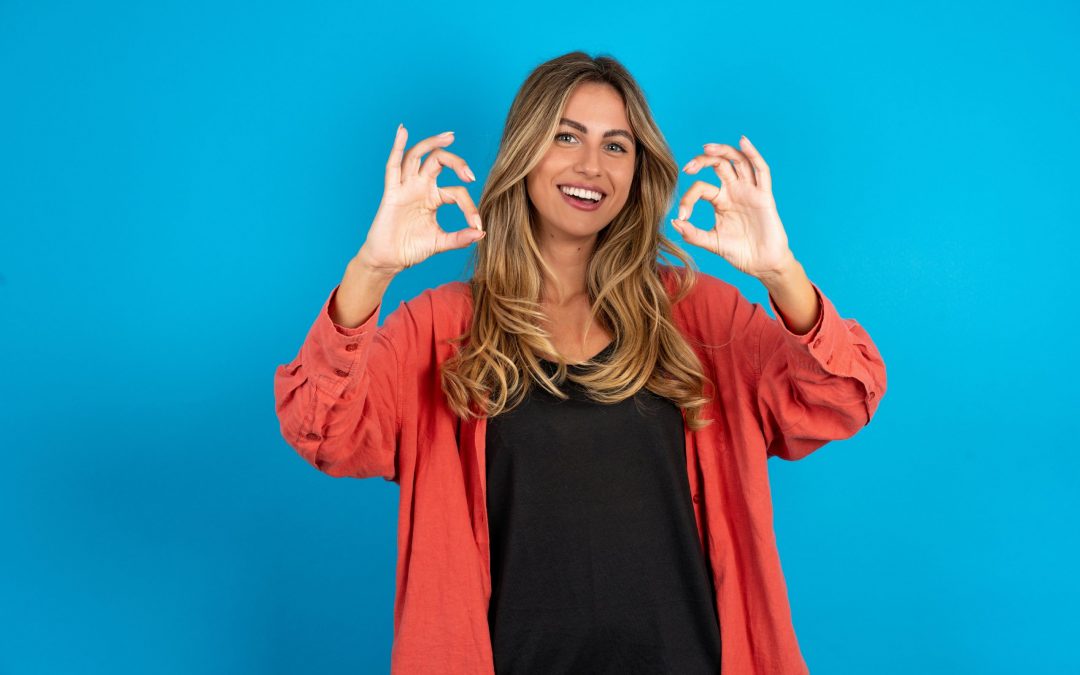 young beautiful blonde woman wearing overshirt showing both hands with fingers in OK sign. Approval or recommending concept